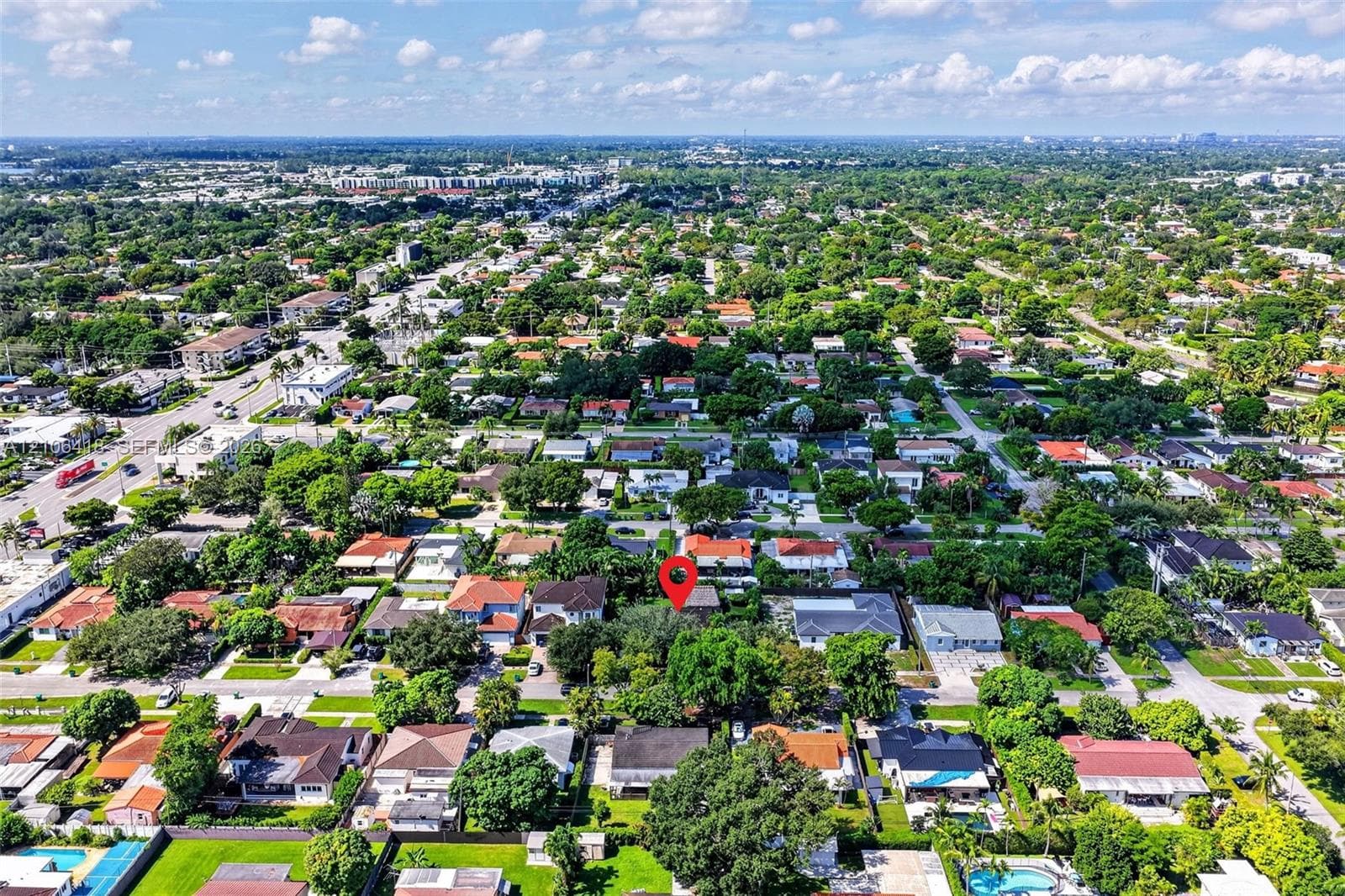 Aerial perspective featuring a residential property situated within a densely landscaped neighborhood with mature tree canopy and established grid infrastructure