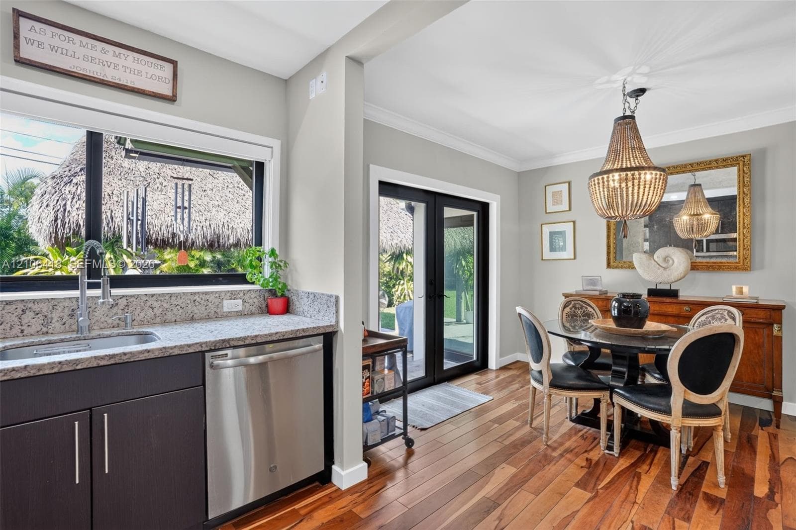 Kitchen featuring wood-finish flooring, dark cabinetry, stone-finish countertops, stainless steel dishwasher, and double glass-paned doors