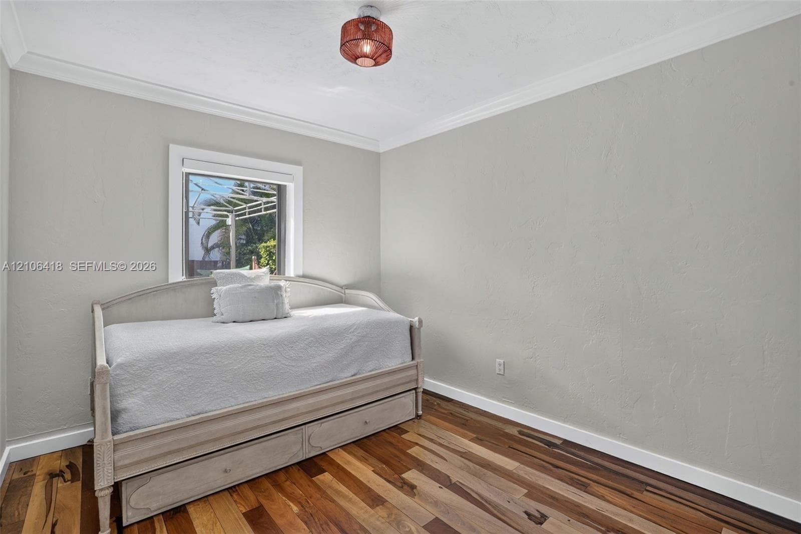 Room featuring wood-finish flooring, textured walls, crown molding, and a drum-style ceiling light fixture