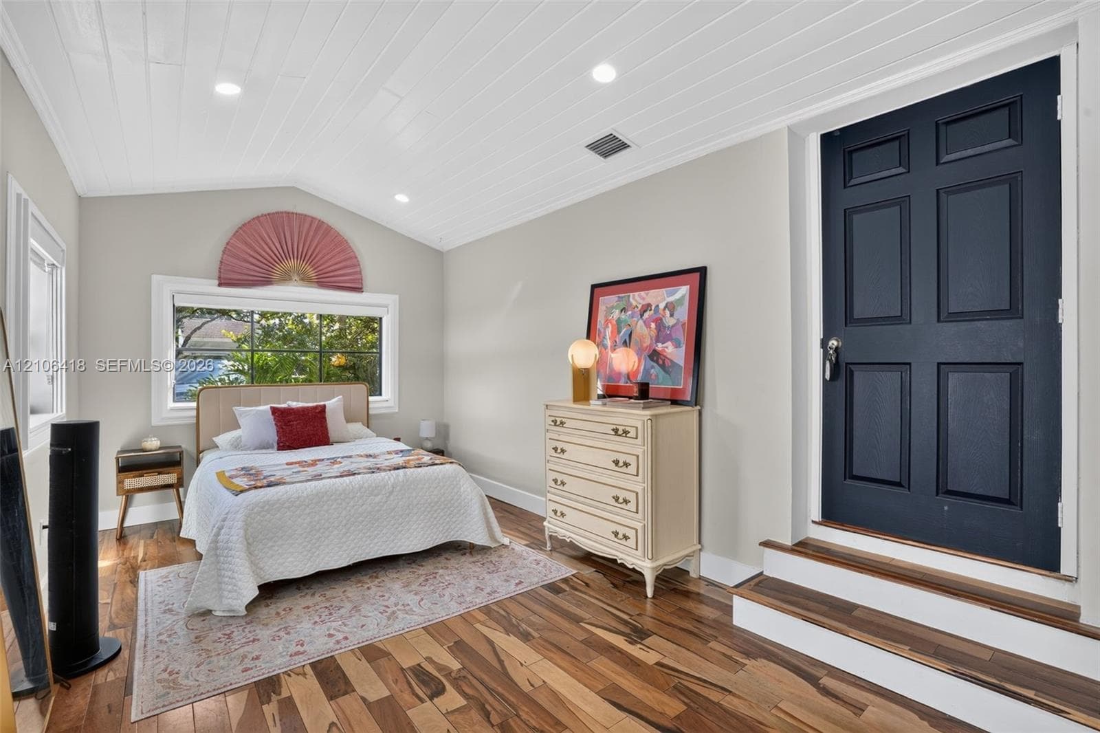 Vaulted ceiling with shiplap paneling, recessed lighting, wood-finish flooring, six-panel solid core door, and window with decorative fan-shaped transom