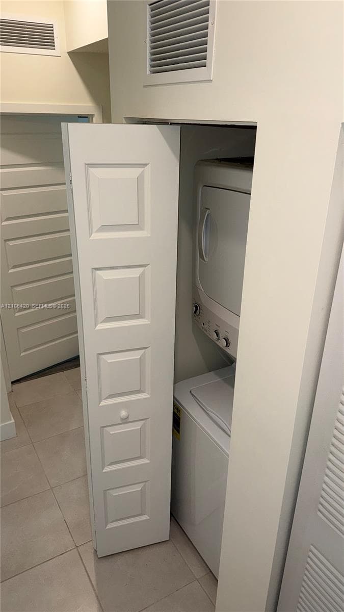Stacked washer and dryer unit concealed behind a five-panel bifold door with ceramic tile flooring