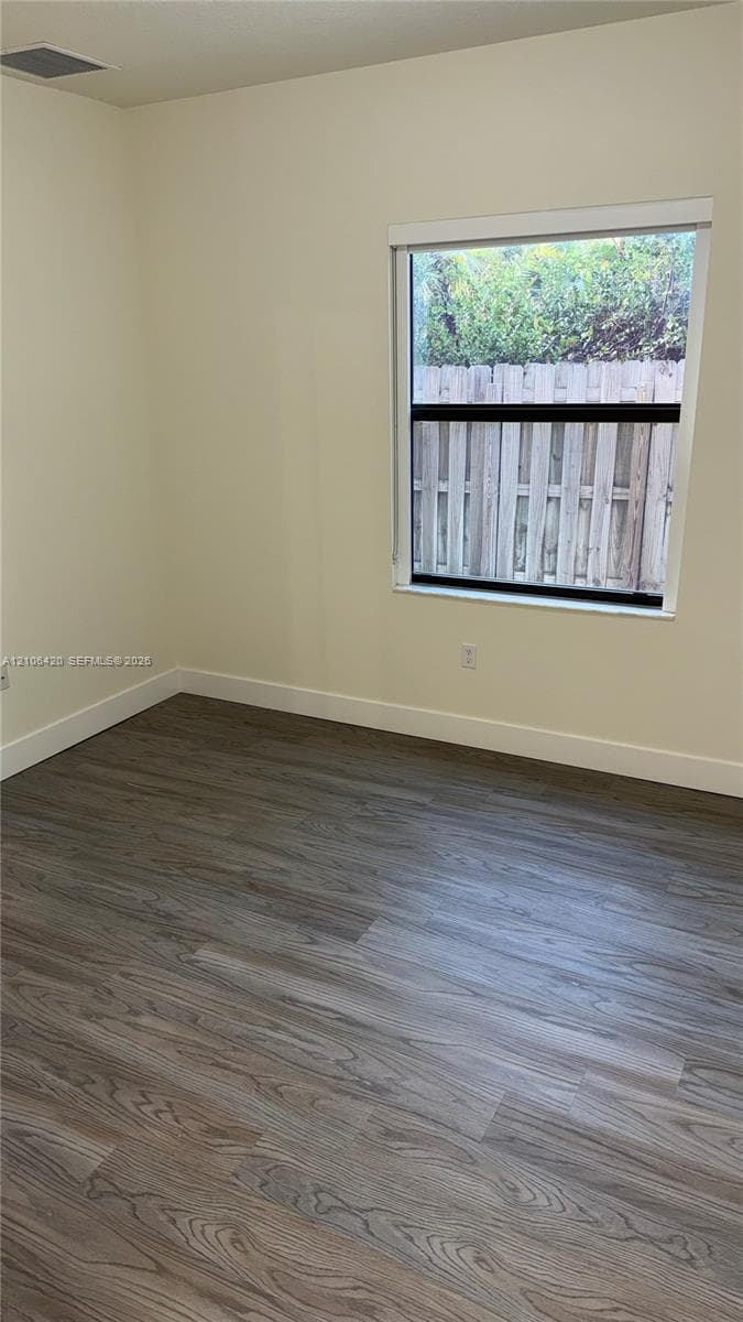 Room featuring wood-finish flooring, neutral wall paint, and a single-pane window with a white frame