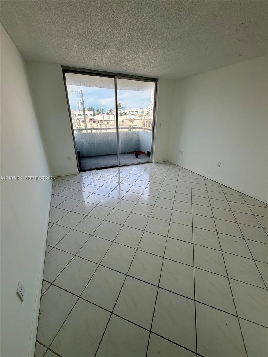 Interior space featuring tile flooring laid on a diagonal and sliding glass doors with access to a concrete balcony