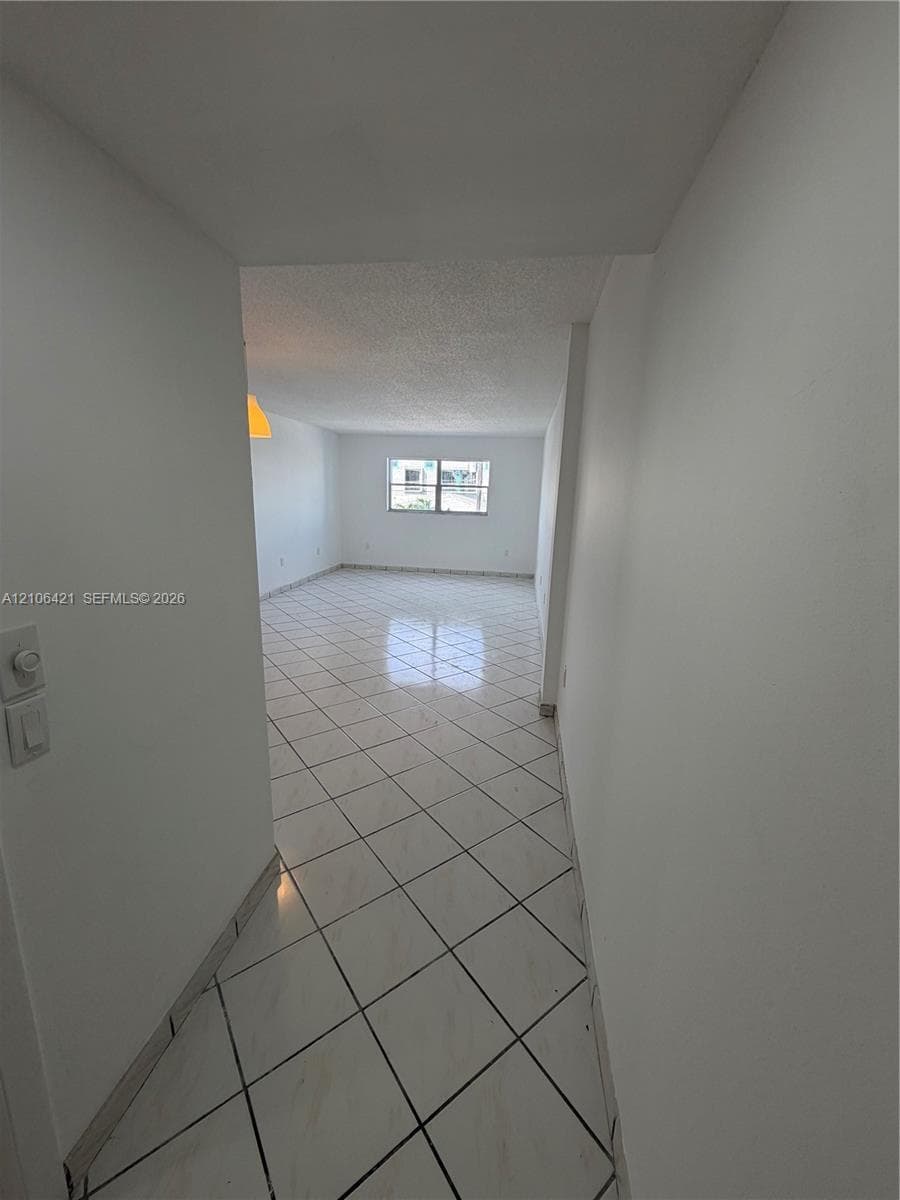 Open-concept area featuring light-toned, diagonal-set tile flooring, smooth ceilings, and white wall finishes