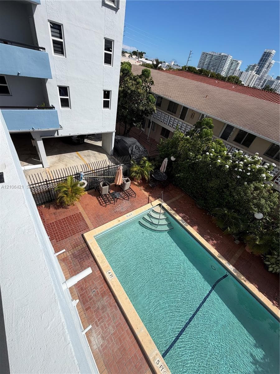 Outdoor swimming pool featuring a masonry surround, built-in steps, and a decorative metal perimeter fence