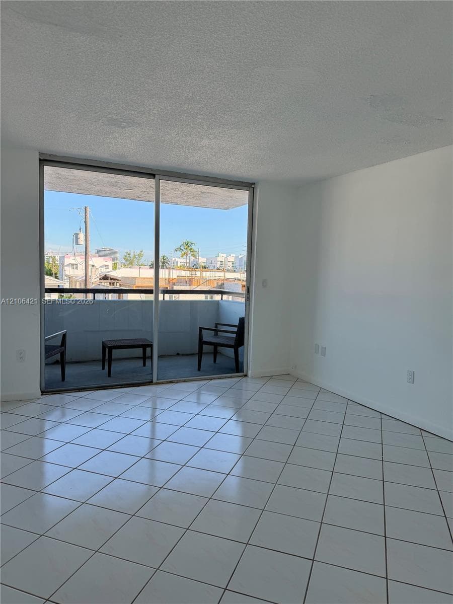 Interior space featuring large-format ceramic tile flooring, sliding glass door, and a private balcony with metal railing
