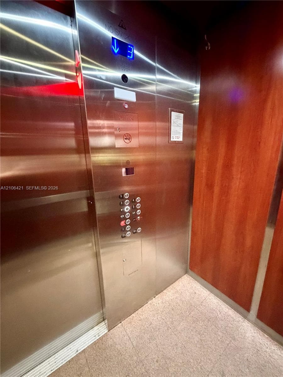 Elevator featuring a stainless steel control panel with digital floor indicator, interior lighting, and wood-finish wall paneling