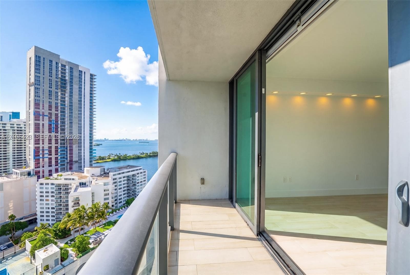 Covered balcony featuring tile flooring, metal railing with glass panels, and sliding glass door entry to interior space with recessed ceiling lighting