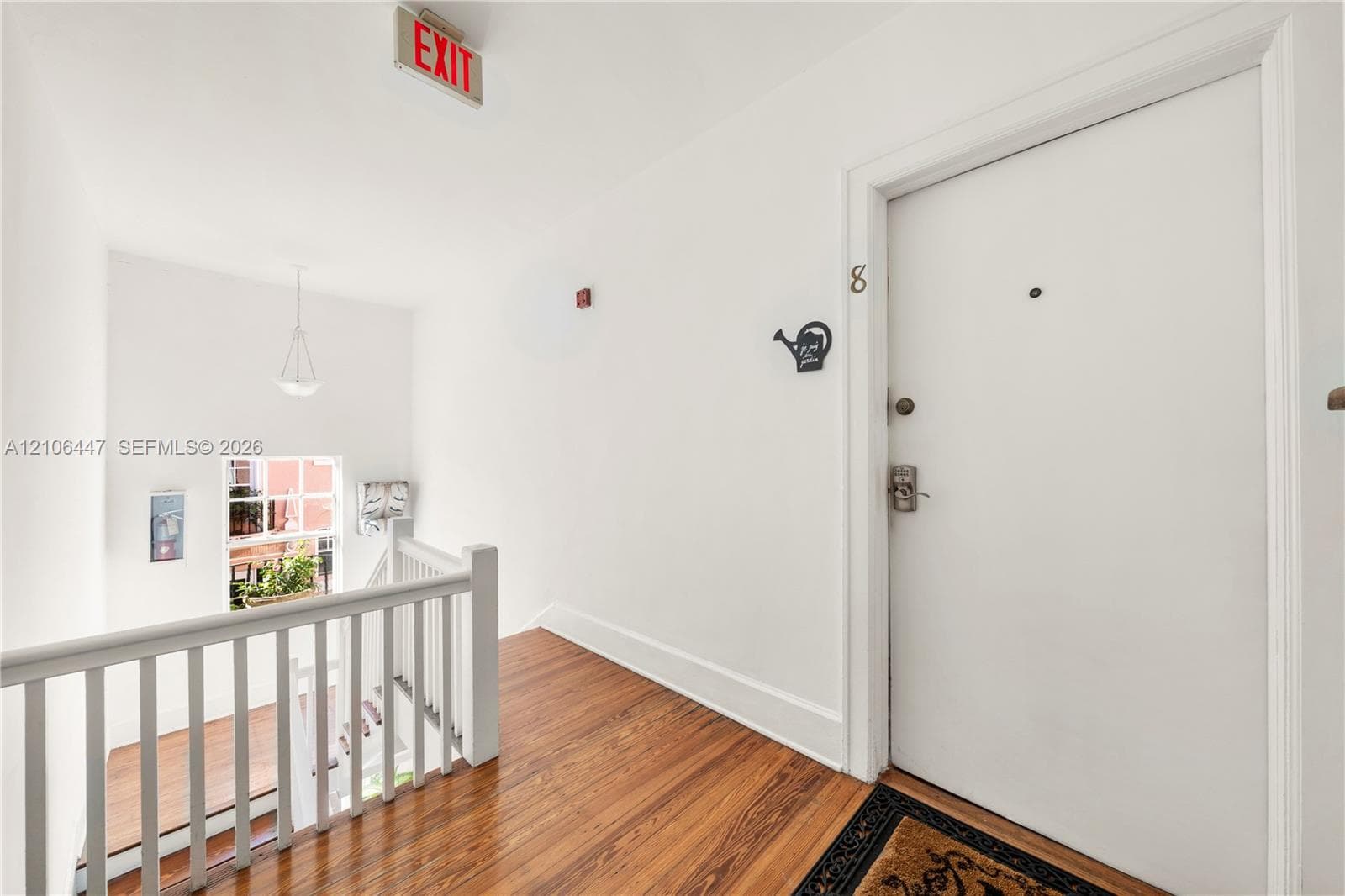 Entryway featuring wood-finish flooring, a white wooden balustrade, and a recessed ceiling pendant light