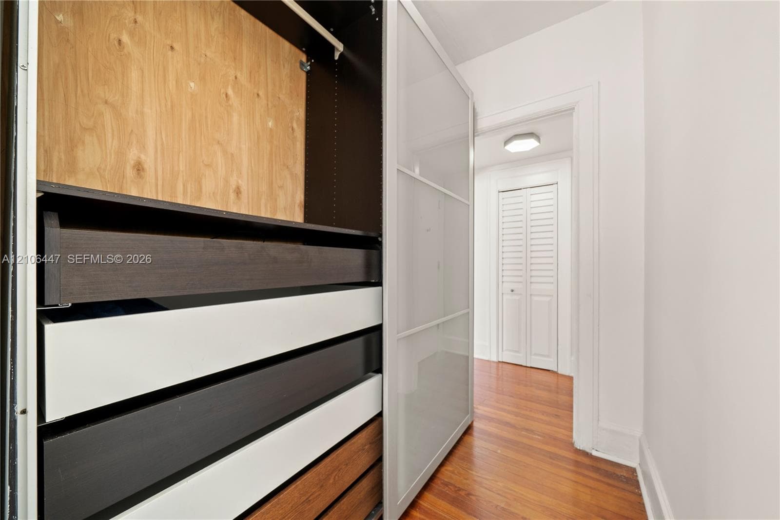 Built-in storage system with sliding glass-paneled doors, wood-finish interior shelving, and deep pull-out drawers