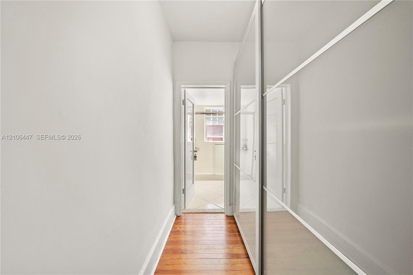 Full-length sliding wardrobe panels featuring a glossy finish and metallic trim, set against wood-finish flooring