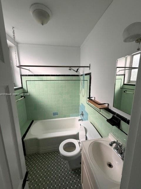 Bathroom featuring a porcelain tub with integrated tile surround, pedestal sink, geometric patterned floor tiling, and wall-mounted vanity mirror