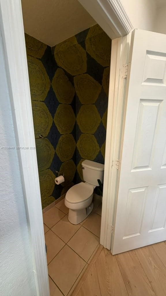 Geometric patterned wallpaper, tile flooring, and a standard-height toilet