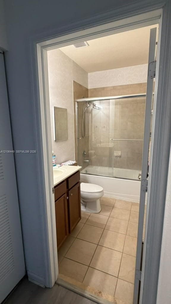 Bathroom featuring a vanity with an integrated sink, tile flooring, and a tub-shower combination with sliding glass doors