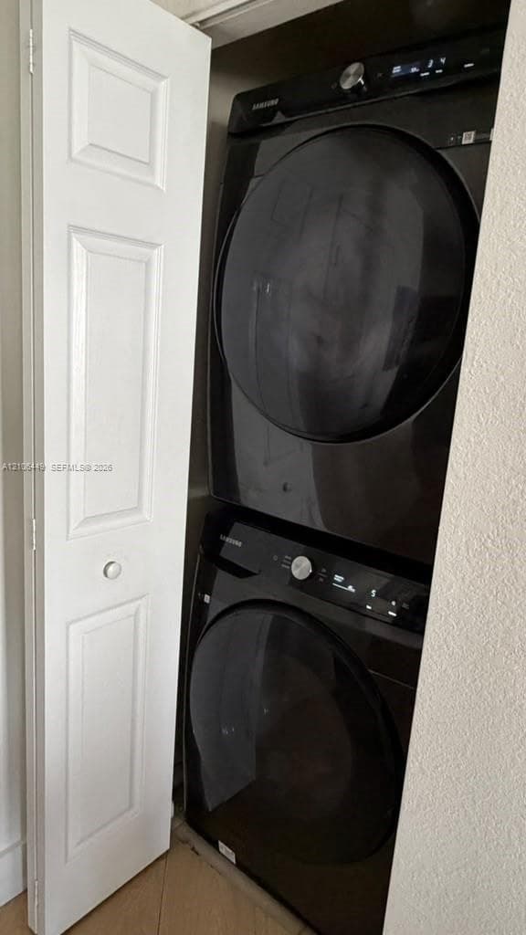 Stacked Samsung laundry center featuring black finish appliances and a white paneled bi-fold door