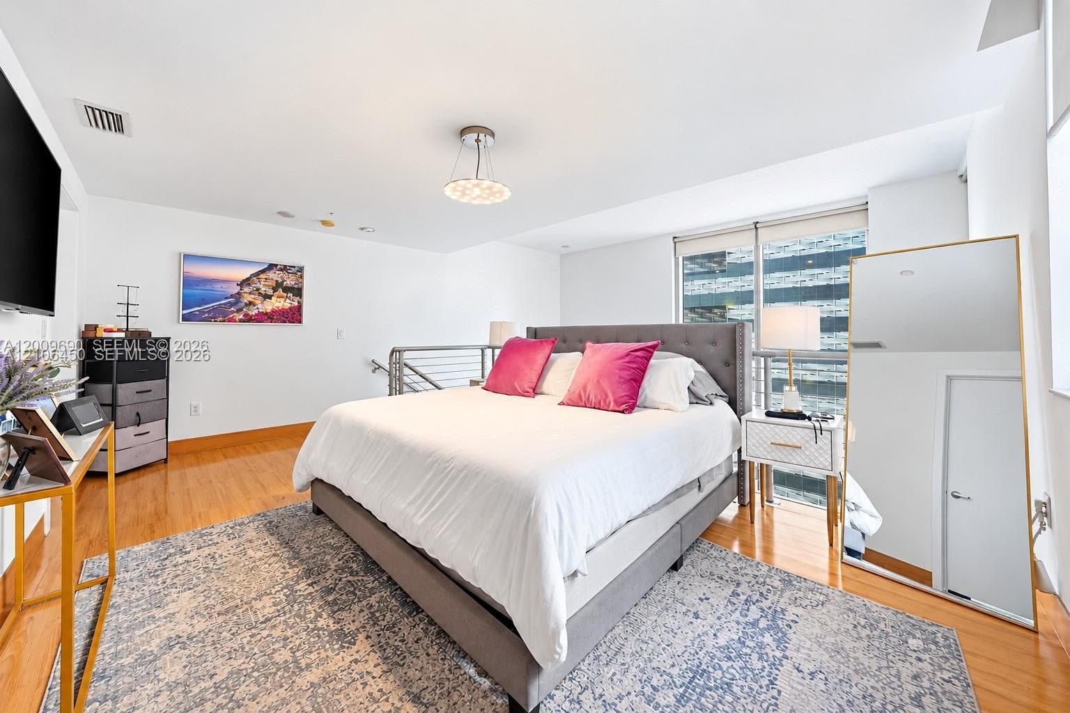 Wood-finish flooring, floor-to-ceiling glass window, stainless steel cable railing, and contemporary pendant lighting