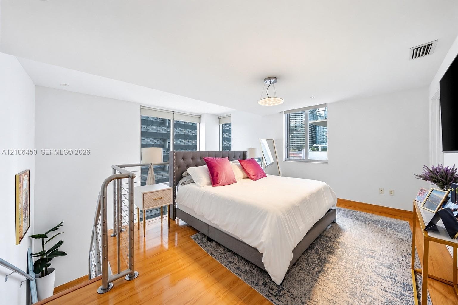 Space featuring wood-finish flooring, large windows, and a metal railing with horizontal cable infill