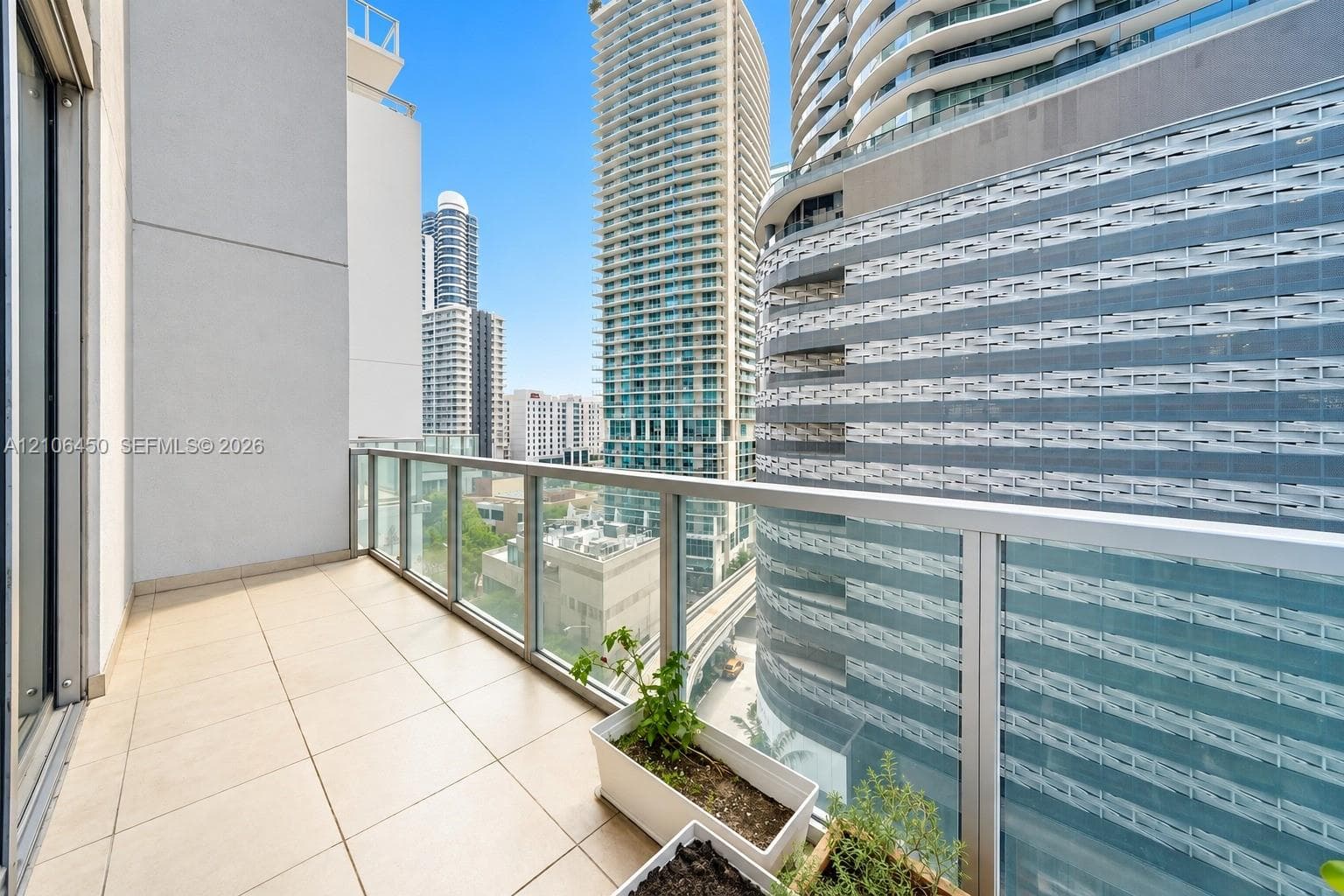 Private balcony featuring light-colored tile flooring and a glass panel railing