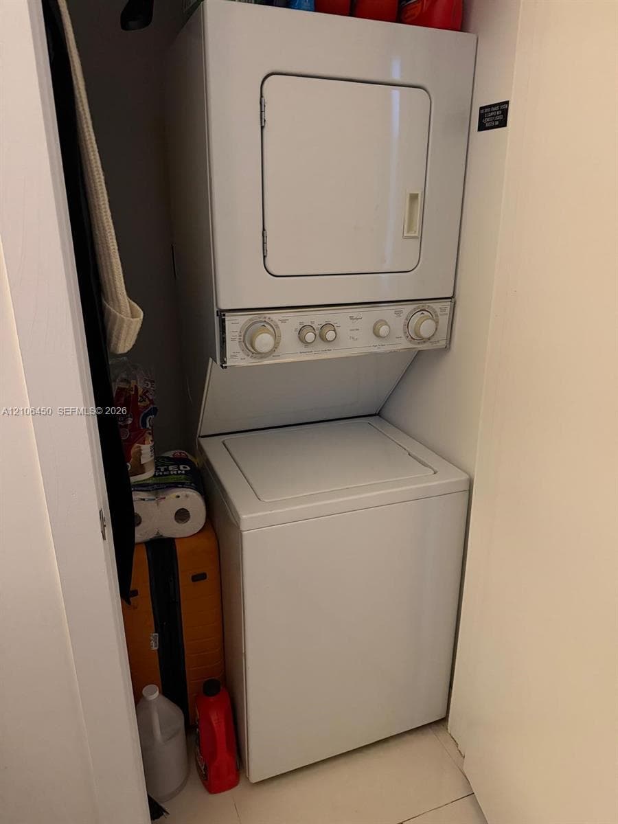 Stacked laundry unit with top-loading washer and front-loading dryer enclosed within a closet