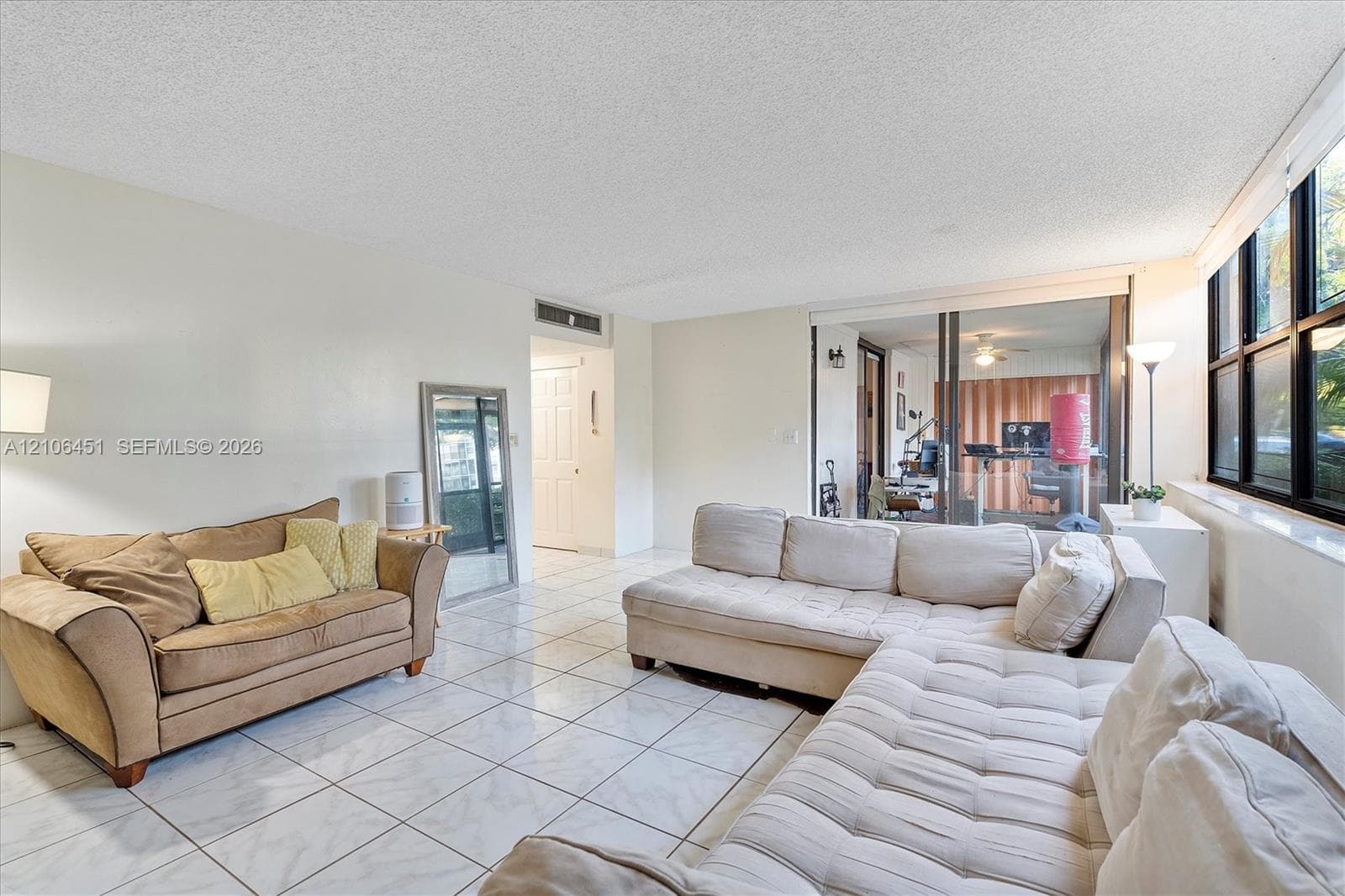 Living area featuring large format tile flooring, floor-to-ceiling windows, and sliding glass doors