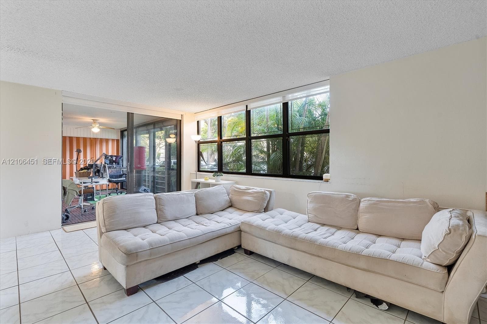 Living area featuring white tile flooring, expansive multi-pane black-frame windows, and sliding glass doors with black frames