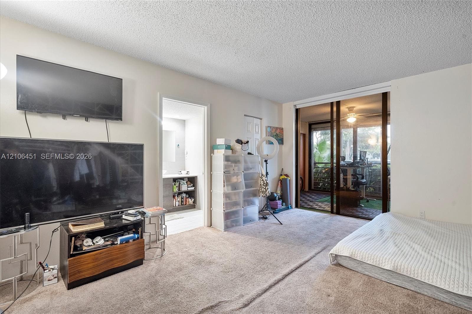 Living area featuring wall-to-wall carpeting, sliding glass doors providing outdoor access, and a built-in vanity cabinet with a stone-finish countertop