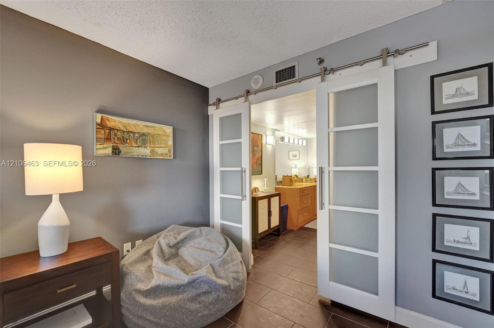 Double sliding doors with frosted glass panels and brushed-metal hardware, featuring a wood-tone vanity with integrated cabinetry and large-format tile flooring