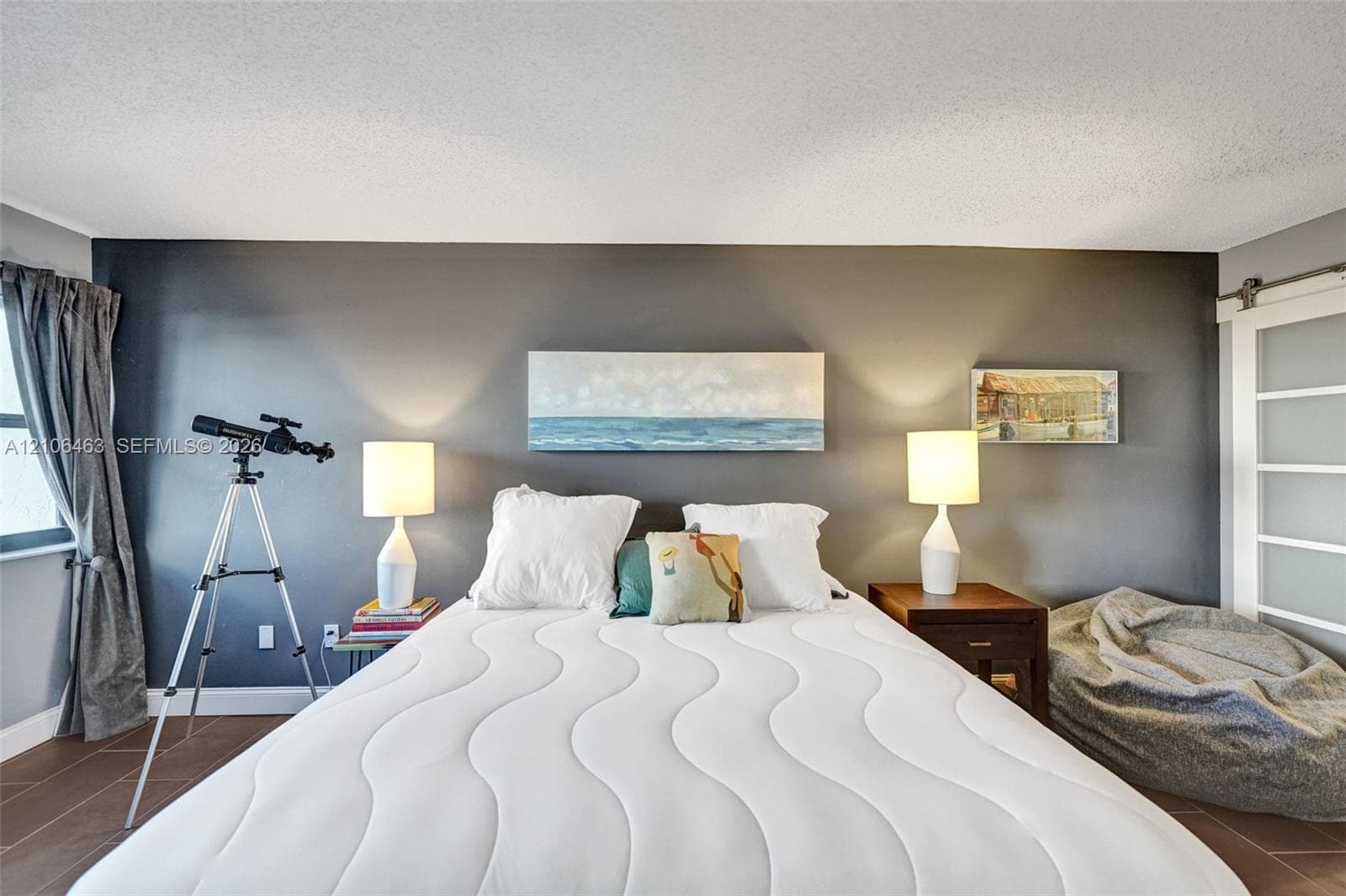 Room featuring charcoal-painted accent wall, large-format tile flooring, and sliding barn-style door with glass panels