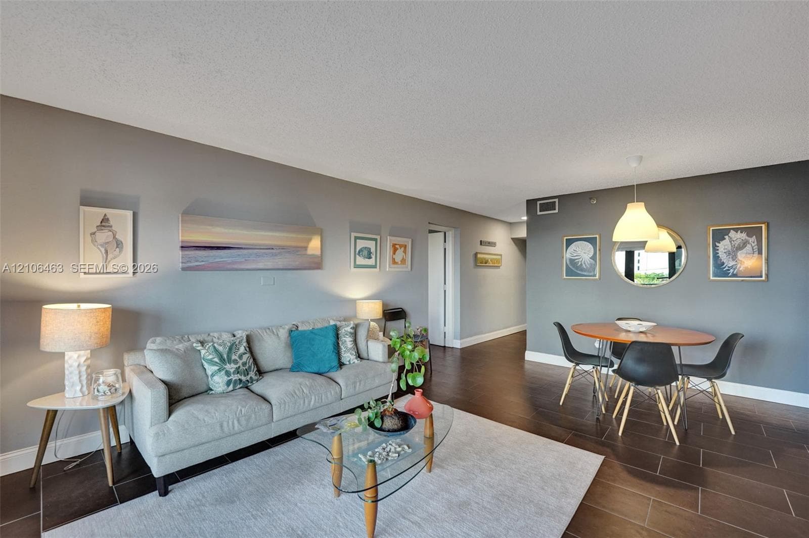 Open-concept main living area featuring dark tile flooring, dual-tone wall finishes, and suspended dome pendant lighting