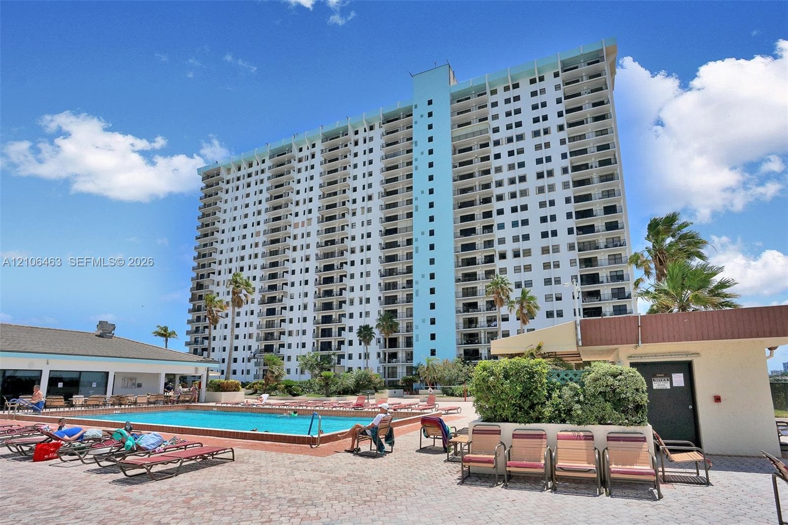 High-rise building featuring private balconies, an outdoor swimming pool, and an expansive paved deck area