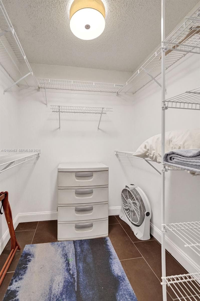 Storage area featuring white wire shelving, dark tile flooring, and a flush-mount overhead light fixture
