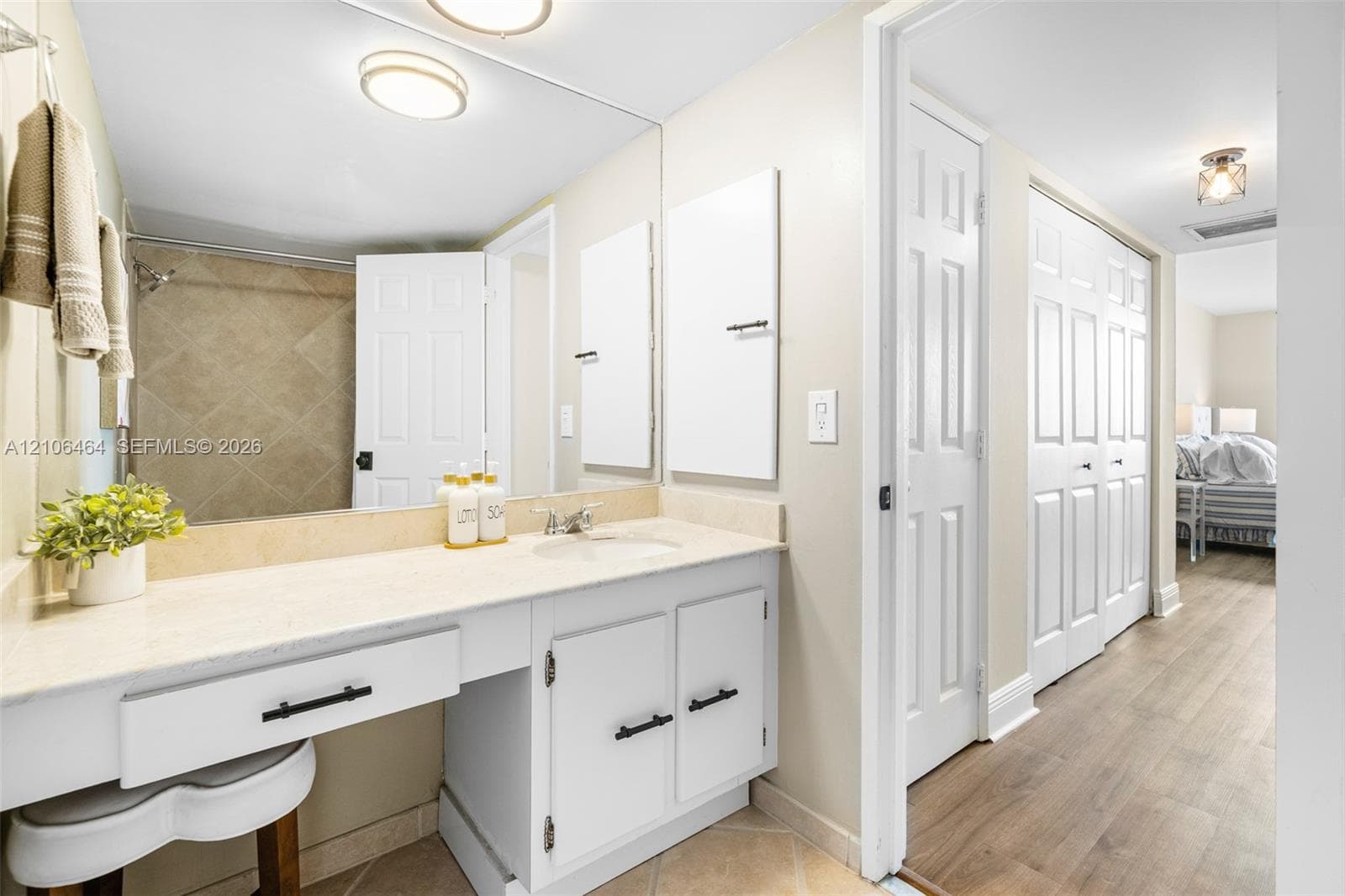 Bathroom featuring a vanity with a light-toned countertop, integrated basin, matte black hardware, and an expansive wall-mounted mirror