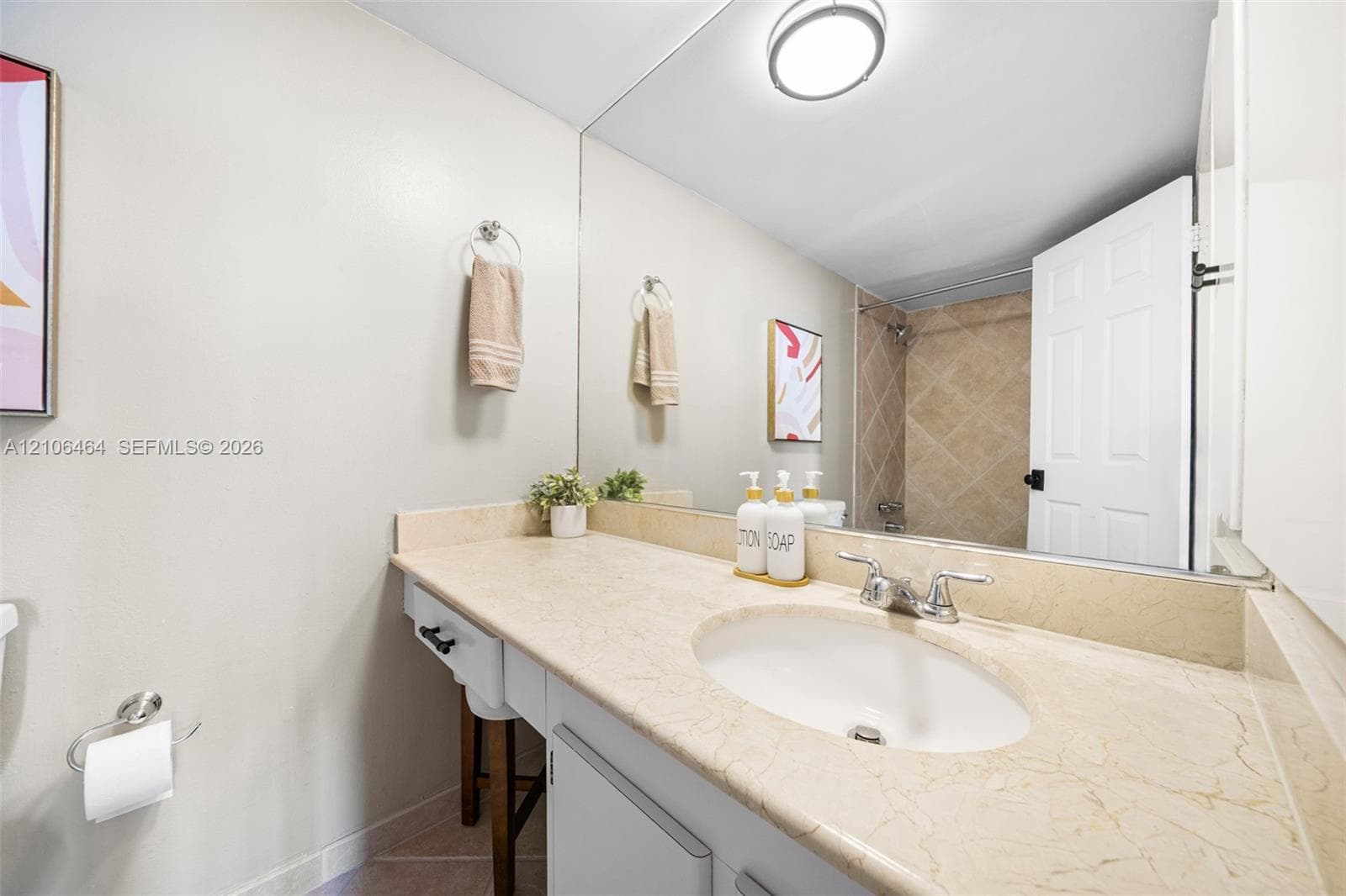 Bathroom featuring a vanity with a stone countertop, oval undermount sink, full-width wall mirror, and a tiled shower surround