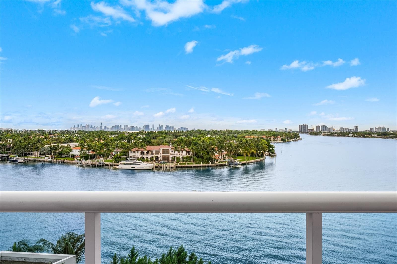 Elevated balcony featuring a tubular metal railing with expansive water, coastline, and skyline scenery