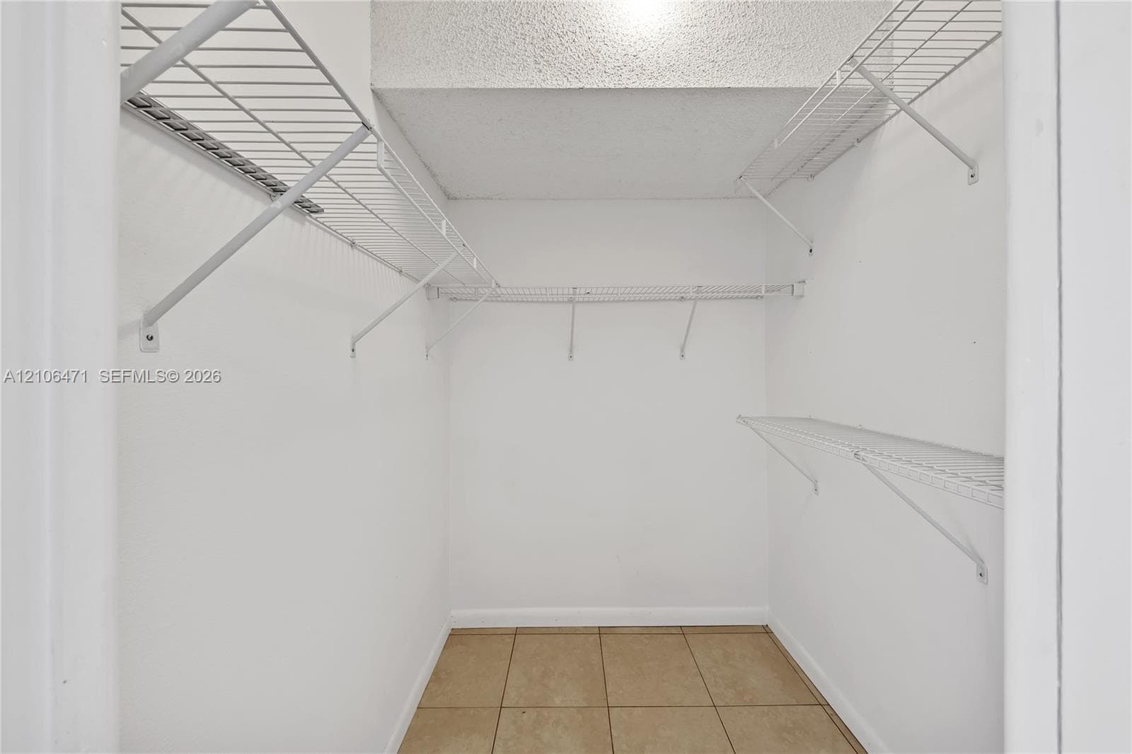 Walk-in closet featuring ceramic tile flooring, neutral wall finishes, and tiered white wire shelving