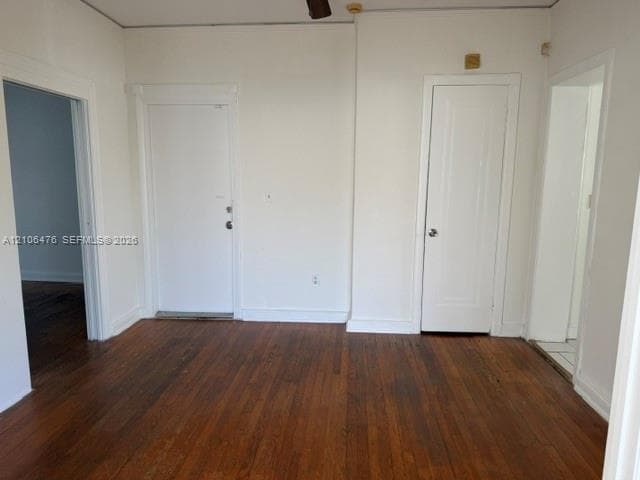 Interior room featuring wood-finish flooring, two solid-core interior doors, and white-painted trim