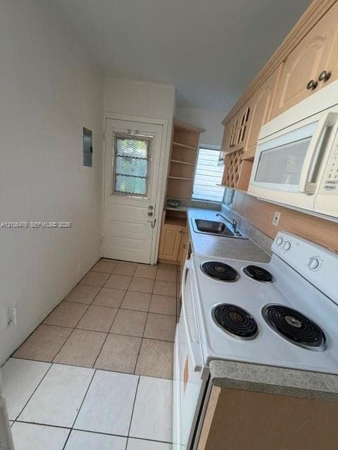 Kitchen featuring light-finish cabinetry with built-in wine storage, white appliances, light-toned countertops, a stainless steel sink, and ceramic tile flooring