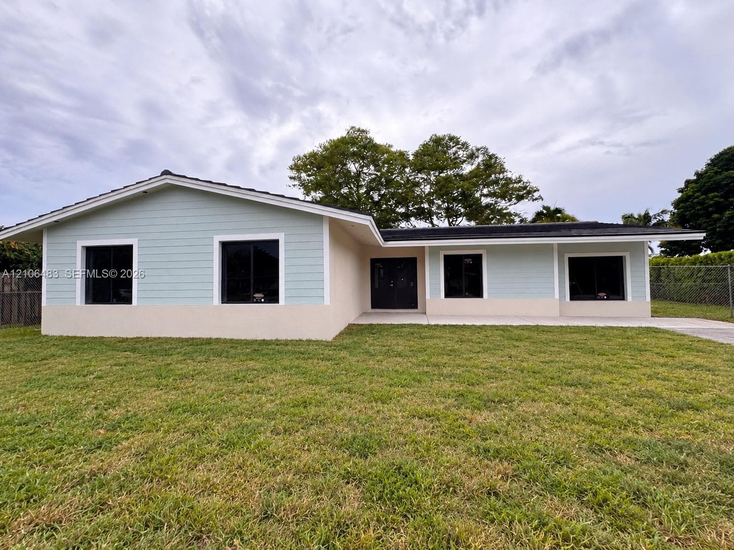 Single-story residence featuring light-toned horizontal siding, a stucco exterior finish, dark-frame windows, and a concrete driveway
