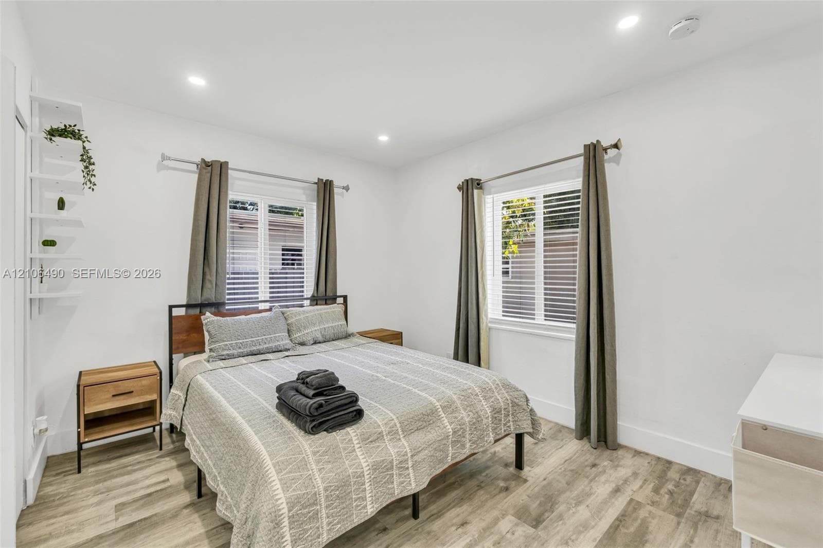 Room featuring wood-finish flooring, dual windows with horizontal blinds, recessed lighting, and built-in wall shelving