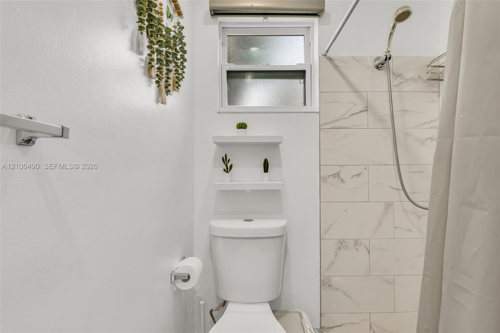 Bathroom featuring a shower stall with large-format stone-patterned wall tile, dual wall-mounted floating shelves, and a high-set window