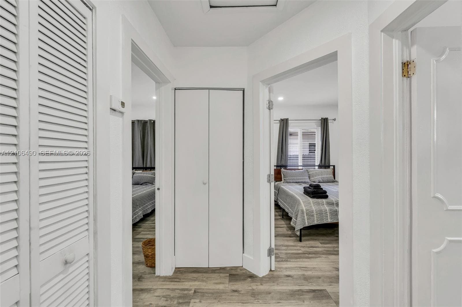Hallway featuring wood-finish flooring, white louvered closet doors, and recessed lighting