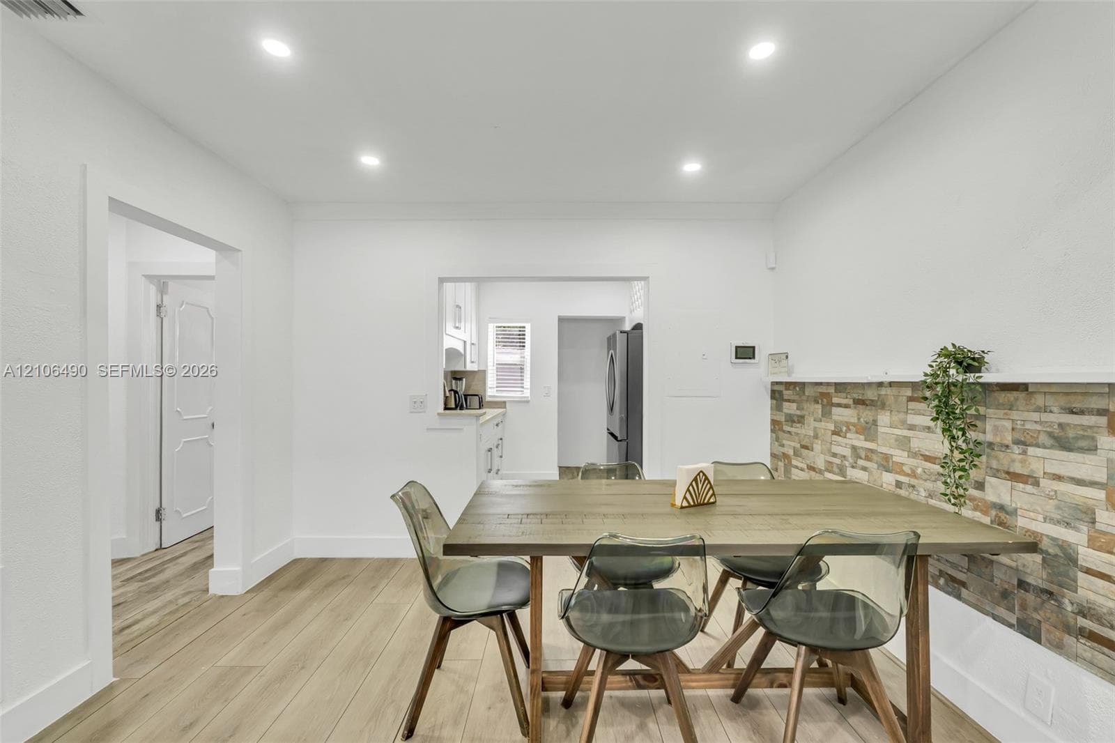 Dining area featuring wood-finish flooring, recessed lighting, and a textured stone-finish accent wall