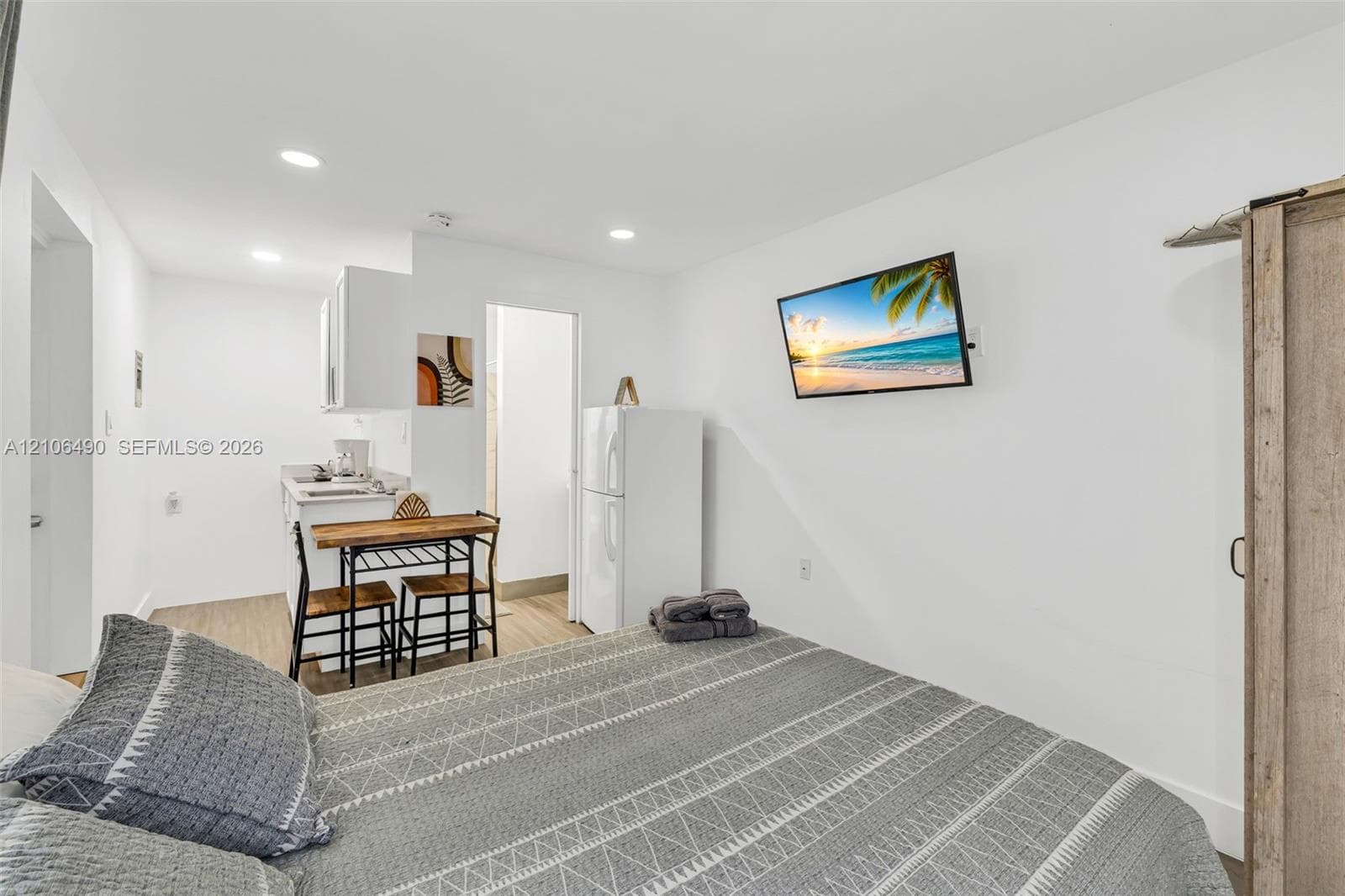 Kitchenette featuring white cabinetry and light-toned wood-finish flooring, illuminated by recessed lighting