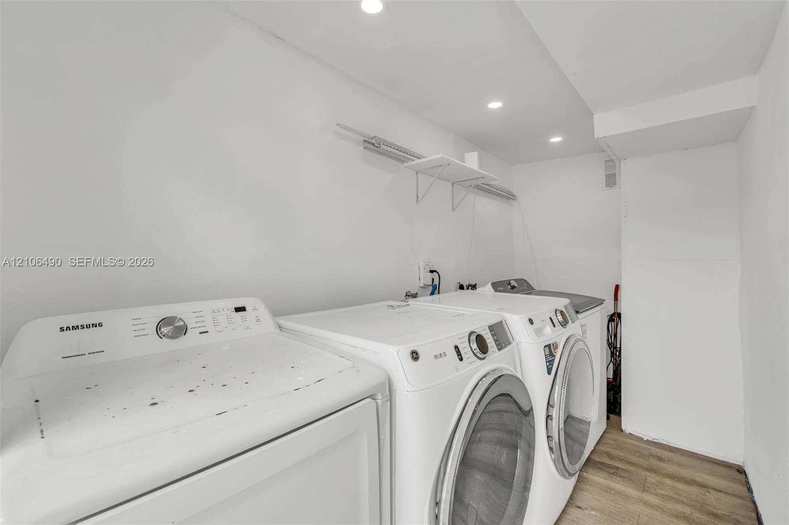 Laundry area featuring wood-finish flooring, recessed lighting, and wall-mounted shelving