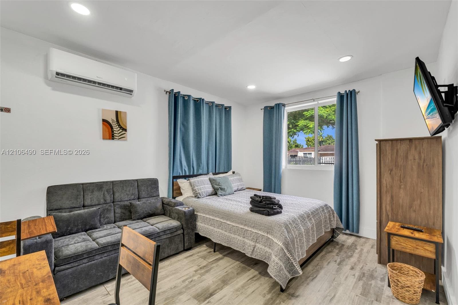Neutral-toned wood-finish flooring, recessed lighting, and a wall-mounted mini-split cooling system