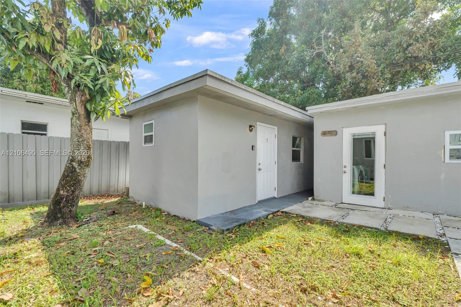 Exterior structure featuring a flat roofline, stucco-finish siding, white paneled entry doors, and concrete paver hardscaping