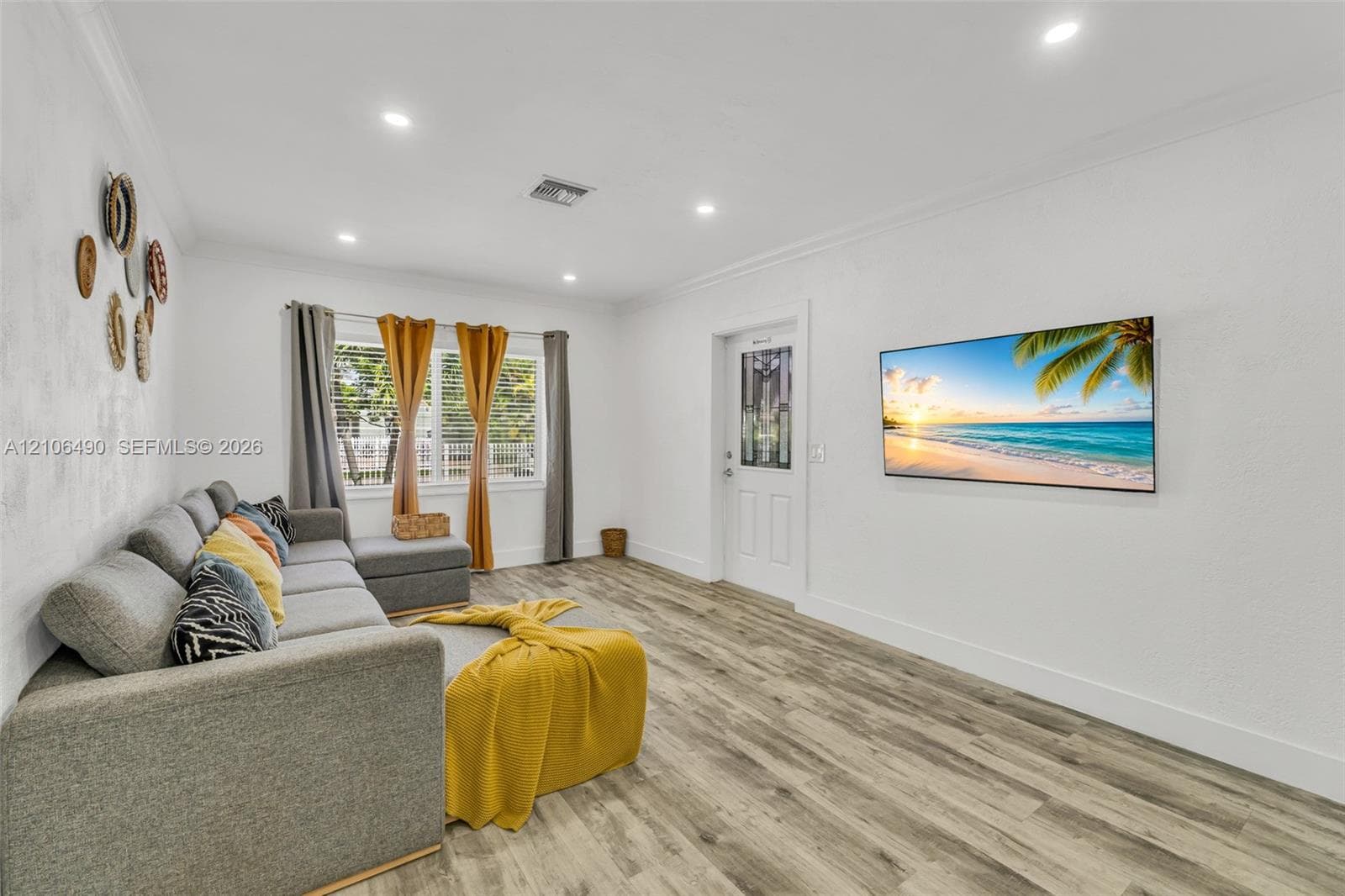 Wood-finish flooring, recessed lighting, crown molding, and a paneled entry door with decorative glass inlay