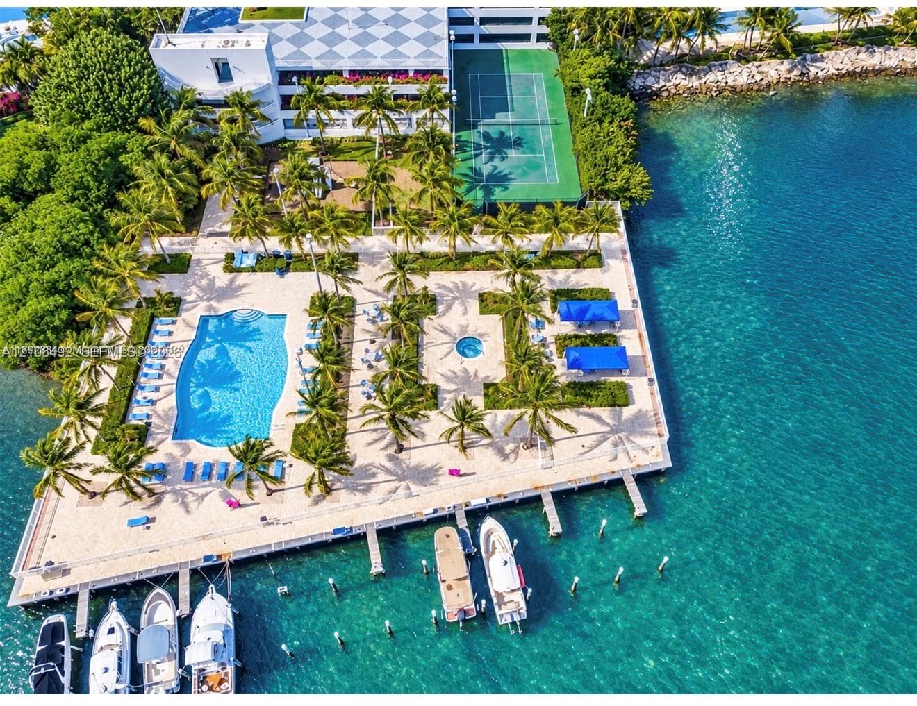 Waterfront grounds featuring a swimming pool, spa, tennis court, and private marina slips