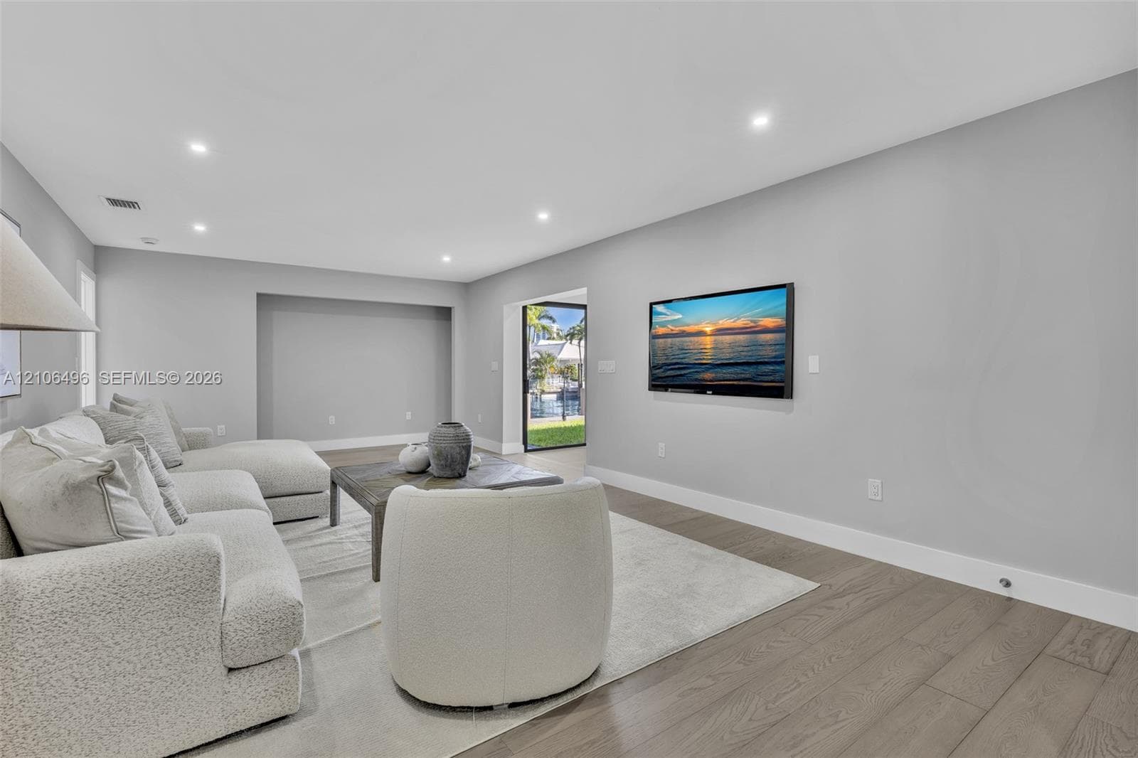 Living area featuring recessed lighting, neutral wall paint, wood-finish flooring, and a recessed wall niche