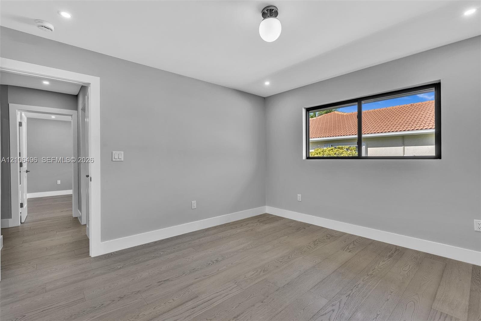 Interior space featuring wood-finish flooring, neutral wall paint, recessed lighting, a globe-style light fixture, and a black-framed window